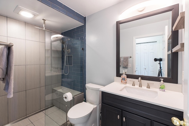 bathroom featuring toilet, vanity, and a tile shower