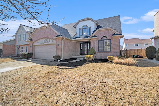 traditional-style home featuring fence, concrete driveway, an attached garage, a shingled roof, and brick siding