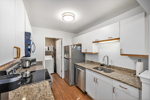 kitchen featuring dark wood-style floors, washer / dryer, a sink, appliances with stainless steel finishes, and white cabinetry