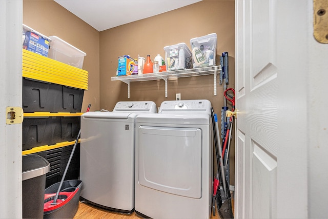 clothes washing area featuring laundry area, wood finished floors, and separate washer and dryer