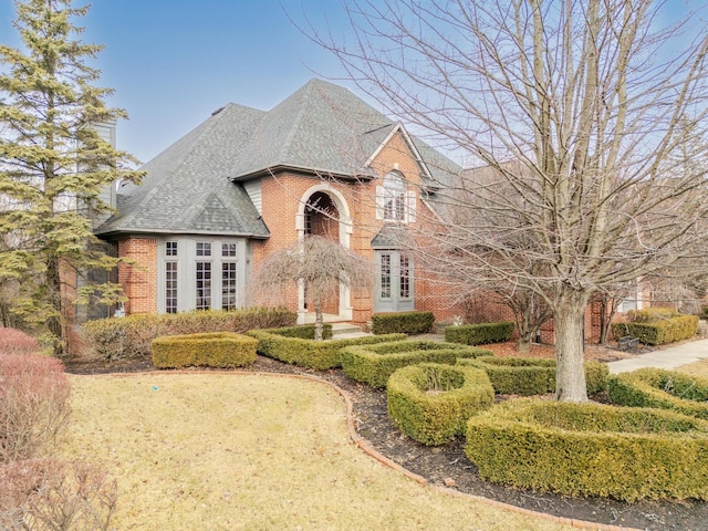 traditional-style house with brick siding, a chimney, and a shingled roof