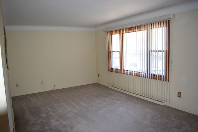 spare room featuring a baseboard heating unit and carpet