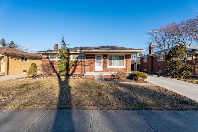 view of front of home with brick siding, a chimney, and a front lawn