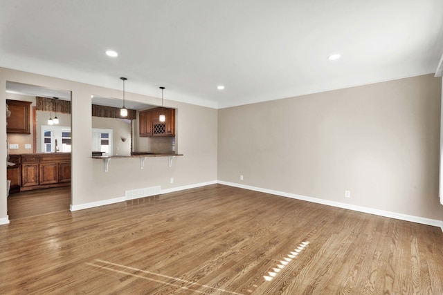 unfurnished living room with recessed lighting, visible vents, baseboards, and wood finished floors