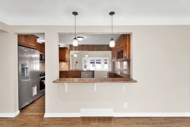 kitchen featuring visible vents, pendant lighting, stainless steel appliances, and wood finished floors