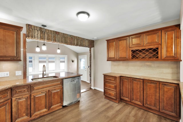 kitchen with brown cabinets, dishwasher, wood finished floors, and a sink