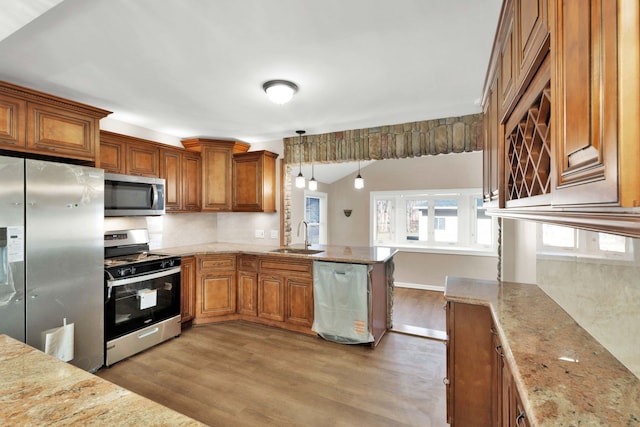 kitchen with a sink, light wood-type flooring, brown cabinets, and stainless steel appliances