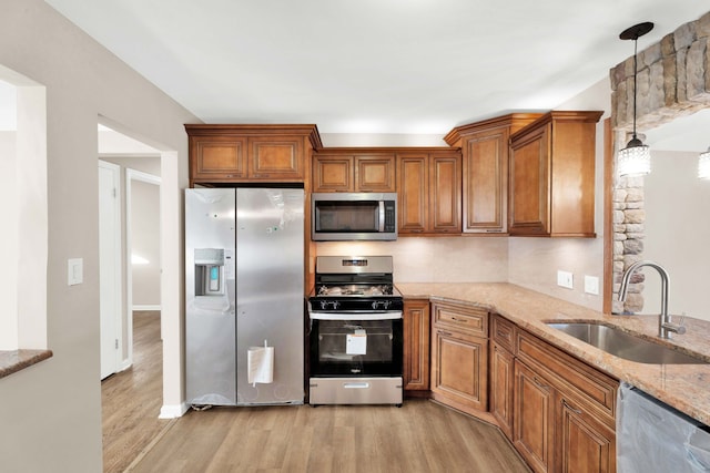 kitchen featuring a sink, brown cabinets, light wood-style floors, and appliances with stainless steel finishes