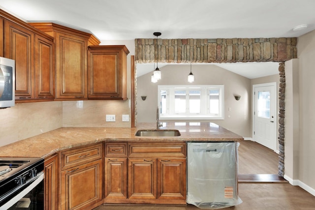 kitchen featuring brown cabinets, dishwasher, light stone countertops, and a sink