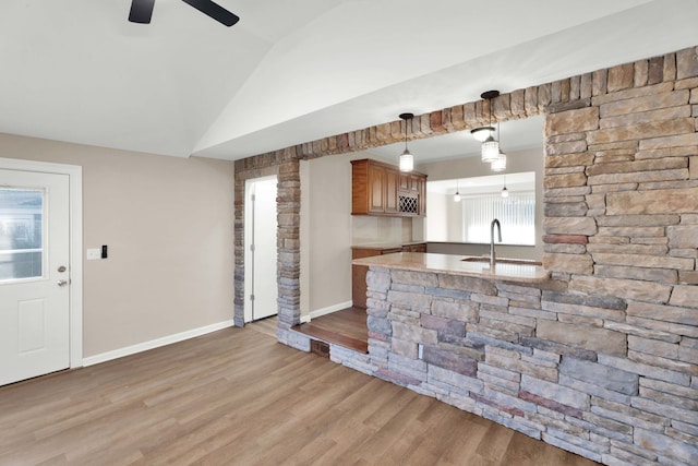 kitchen with light wood-type flooring, a sink, baseboards, light countertops, and lofted ceiling