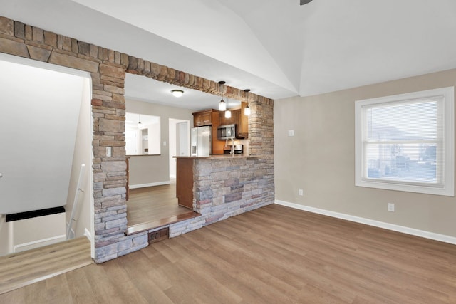 unfurnished living room with vaulted ceiling, wood finished floors, baseboards, and visible vents