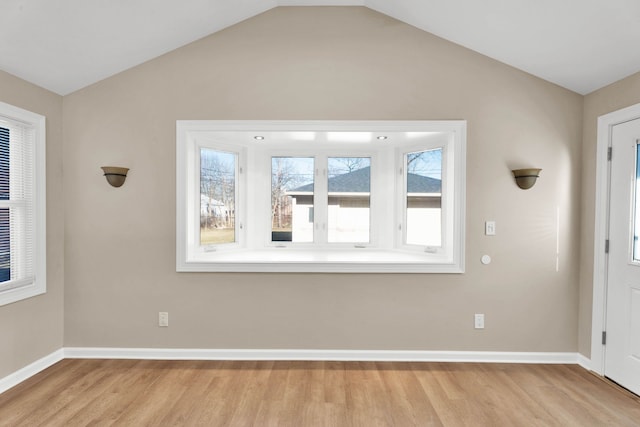 entrance foyer featuring lofted ceiling, baseboards, and light wood finished floors