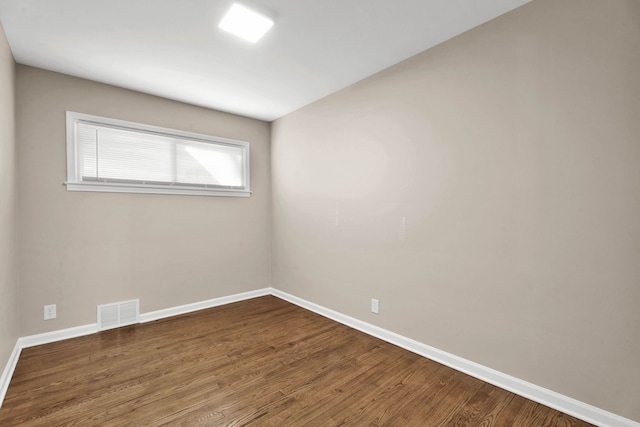 unfurnished room featuring visible vents, baseboards, and wood finished floors