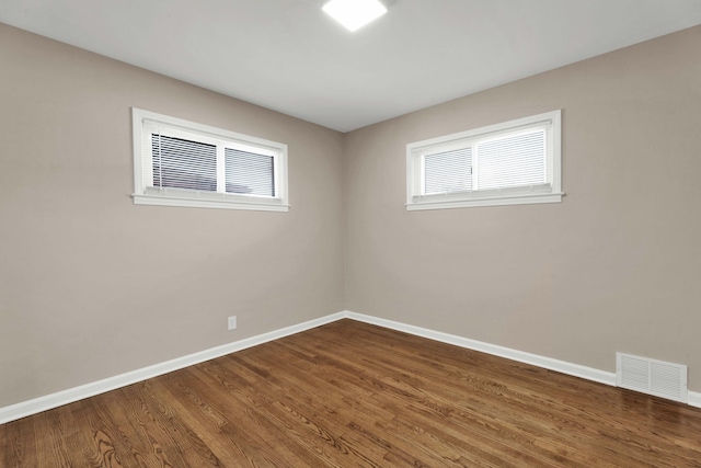 spare room with visible vents, baseboards, plenty of natural light, and dark wood finished floors