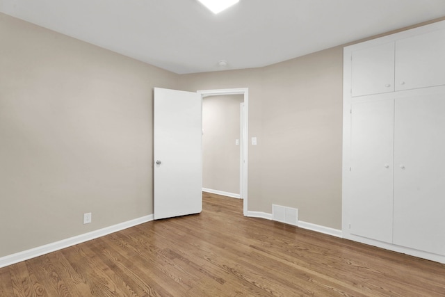 unfurnished bedroom with light wood-style flooring, baseboards, visible vents, and a closet