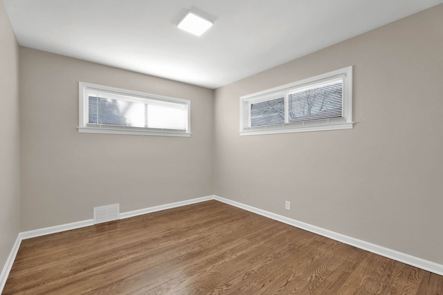 empty room with visible vents, baseboards, and wood finished floors