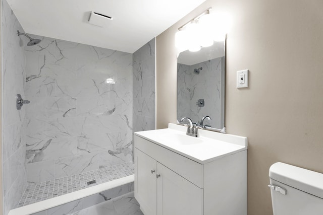 full bath featuring toilet, marble finish floor, a stall shower, and vanity