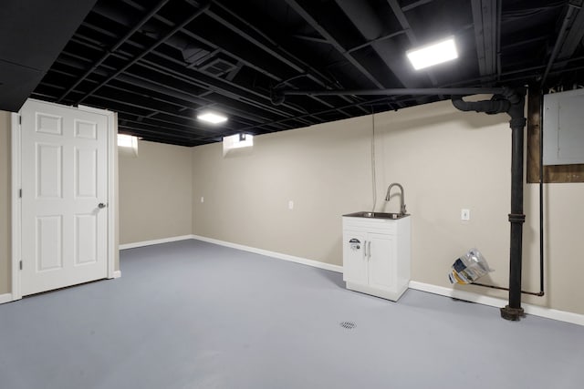 finished below grade area featuring electric panel, baseboards, and a sink