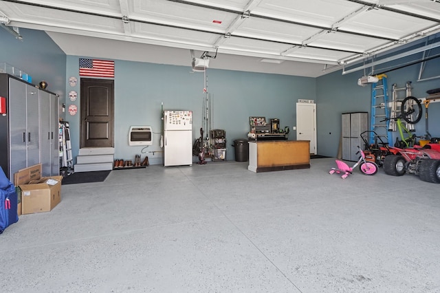 garage featuring heating unit, a garage door opener, and freestanding refrigerator