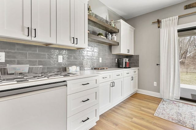 kitchen featuring dishwasher, light countertops, light wood-style flooring, white cabinets, and open shelves