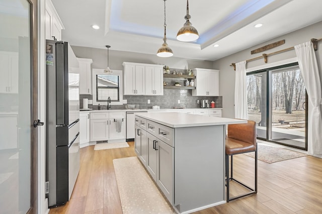 kitchen with a raised ceiling, light wood-style flooring, light countertops, and tasteful backsplash