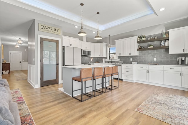 kitchen with a breakfast bar area, white cabinets, refrigerator, a raised ceiling, and stainless steel dishwasher