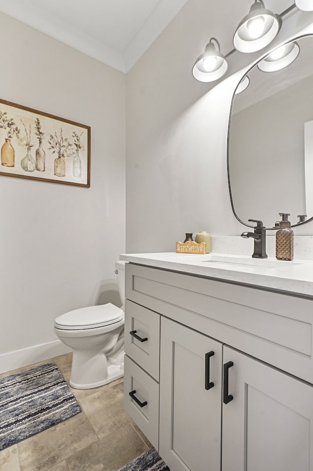 bathroom featuring vanity, crown molding, toilet, and baseboards