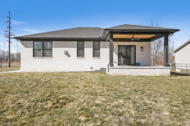 rear view of property featuring a patio area, a yard, a ceiling fan, and brick siding