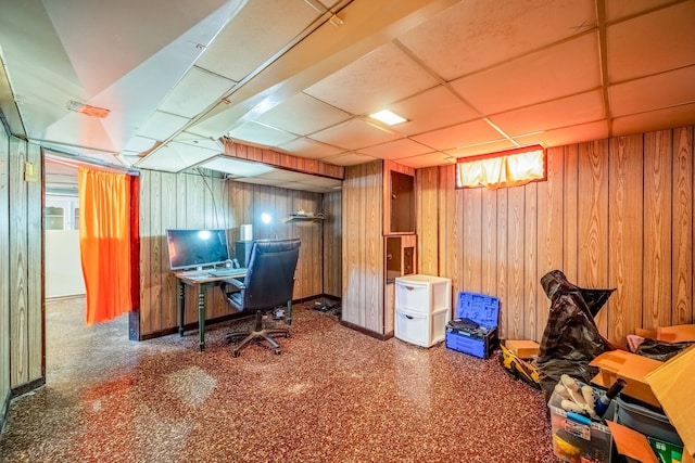 office space featuring a paneled ceiling and wood walls