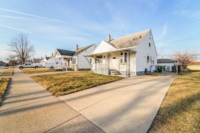 bungalow-style house featuring a porch, a chimney, driveway, and a front lawn