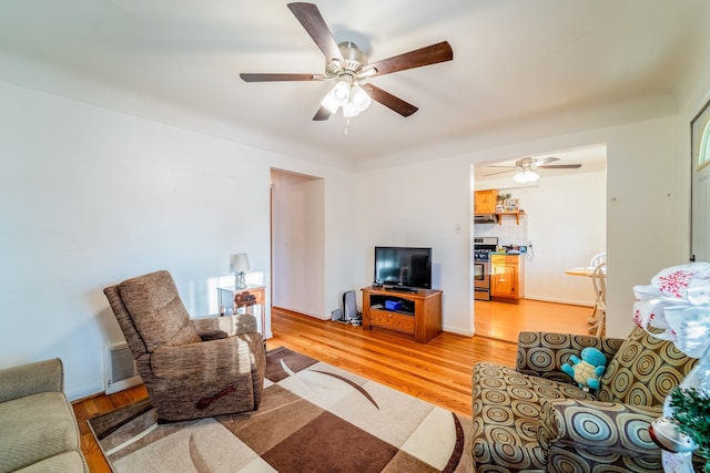 living area with a ceiling fan, light wood-style floors, visible vents, and baseboards