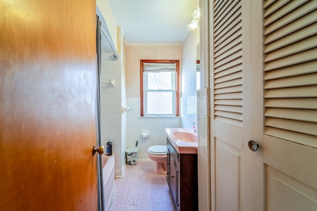 full bathroom featuring toilet, tile walls, wainscoting, tile patterned flooring, and vanity