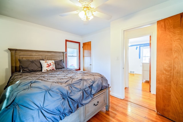 bedroom featuring visible vents, multiple windows, light wood-style floors, and baseboards