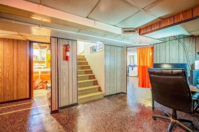 basement with stairway, wooden walls, visible vents, and baseboards