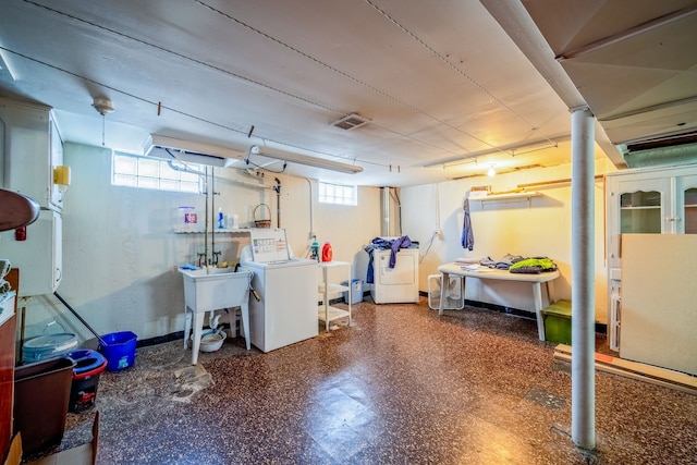 below grade area featuring a sink, washing machine and dryer, baseboards, and a healthy amount of sunlight