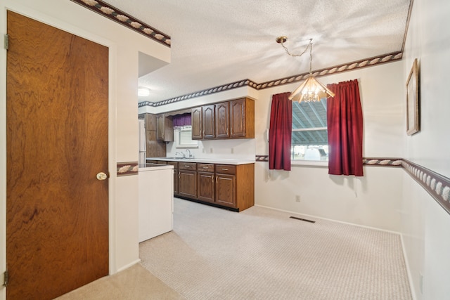 kitchen featuring visible vents, a sink, light countertops, a textured ceiling, and a notable chandelier