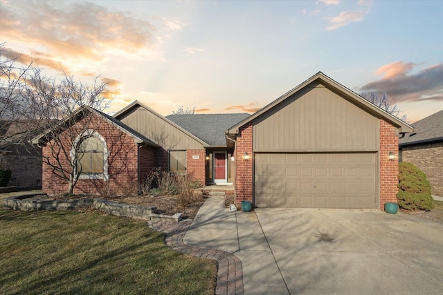 ranch-style home with an attached garage, a shingled roof, concrete driveway, a lawn, and brick siding