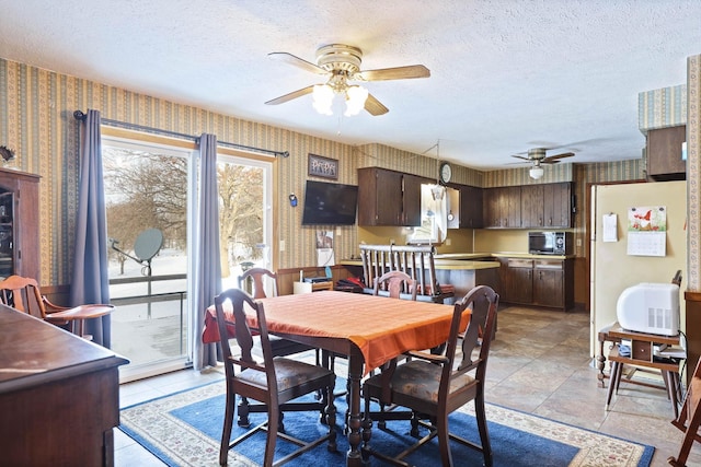 dining area featuring a textured ceiling, ceiling fan, and wallpapered walls