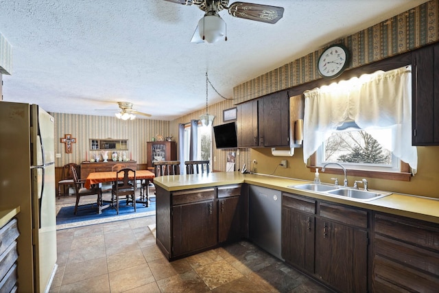 kitchen with ceiling fan, a sink, freestanding refrigerator, a peninsula, and wallpapered walls