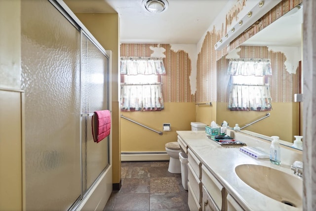 bathroom featuring vanity, toilet, stone finish flooring, a baseboard radiator, and bath / shower combo with glass door