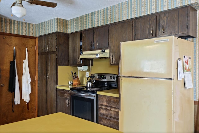 kitchen with stainless steel electric range, light countertops, freestanding refrigerator, wallpapered walls, and under cabinet range hood