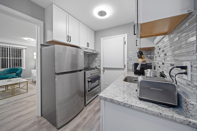 kitchen featuring light wood-style flooring, under cabinet range hood, backsplash, appliances with stainless steel finishes, and white cabinets