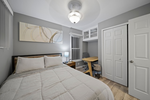 bedroom featuring a closet, light wood-type flooring, and a ceiling fan