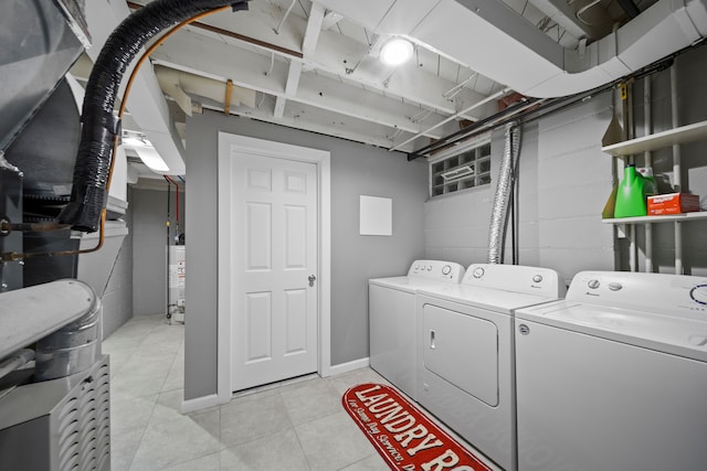 clothes washing area with water heater, laundry area, light tile patterned floors, independent washer and dryer, and concrete block wall