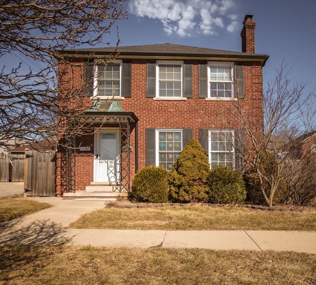 colonial house featuring brick siding and a chimney