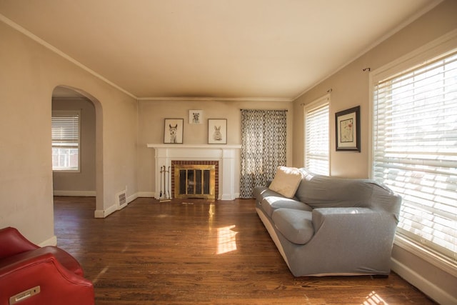 living room featuring visible vents, wood finished floors, arched walkways, and ornamental molding