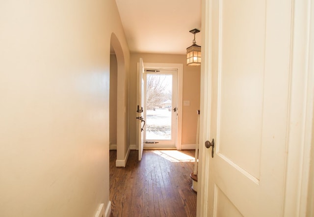 doorway featuring dark wood-style floors, baseboards, and arched walkways