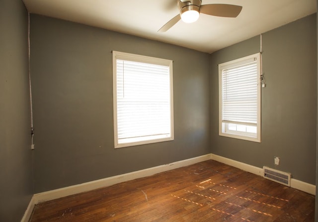 unfurnished room featuring dark wood-type flooring, baseboards, visible vents, and ceiling fan