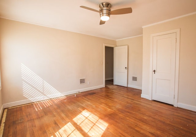 unfurnished bedroom with ornamental molding, wood finished floors, visible vents, and baseboards