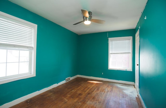 empty room featuring baseboards, visible vents, wood-type flooring, and ceiling fan